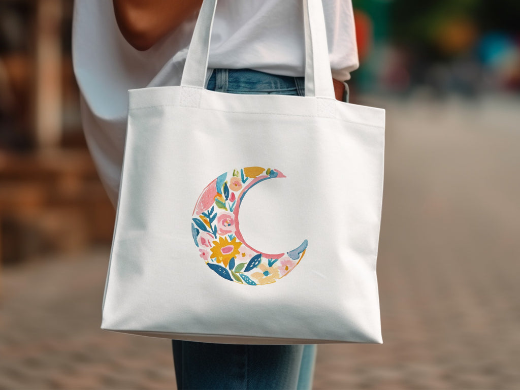 White tote bag with a floral crescent moon design.