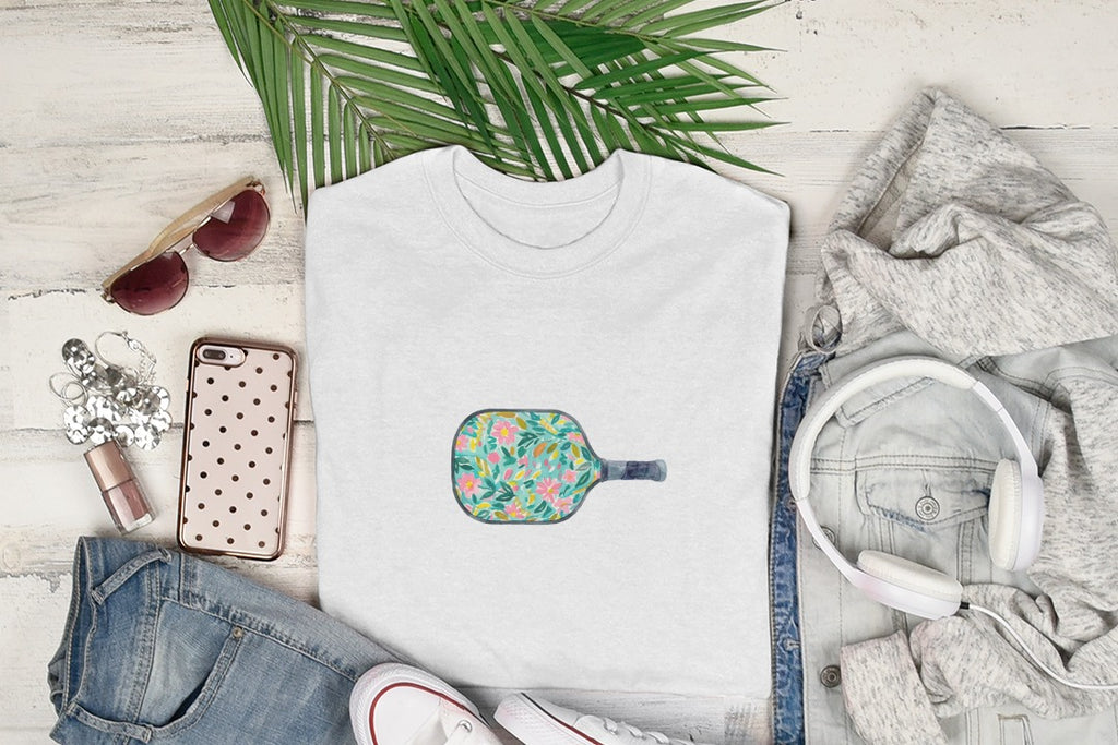 White t-shirt with a colorful floral pickleball paddle graphic.