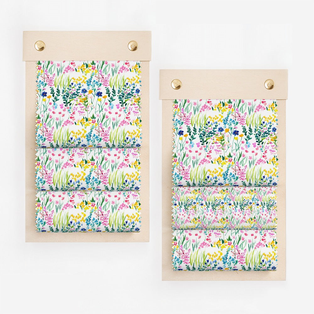 Two fabric swatches with a colorful floral wildflower print on a light wood backing.
