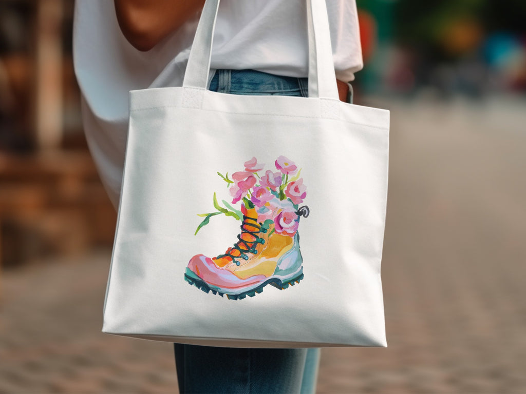 White tote bag with a watercolor illustration of a hiking boot adorned with flowers.