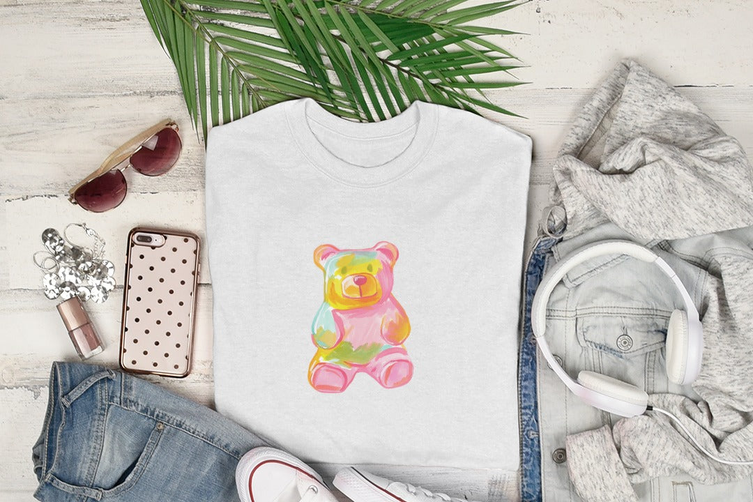 White t-shirt with a colorful gummy bear graphic, laid flat with accessories.
