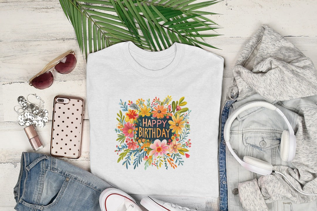 White t-shirt with floral "Happy Birthday" graphic, styled with jeans and headphones.