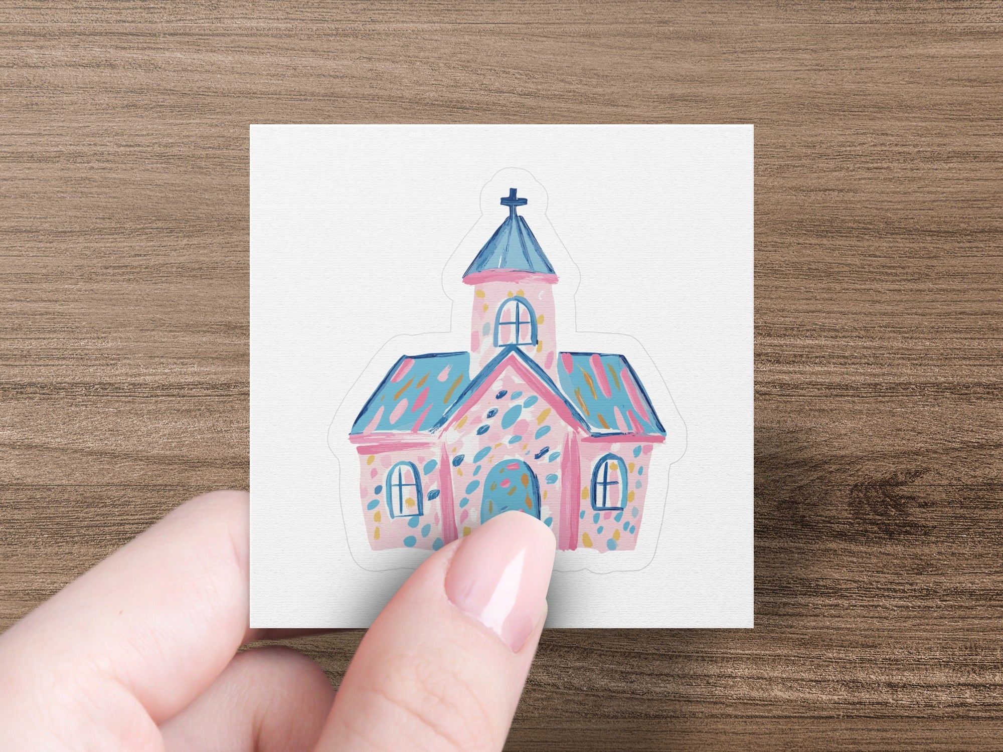Pink and blue cottage with arched windows and a cross on the roof.