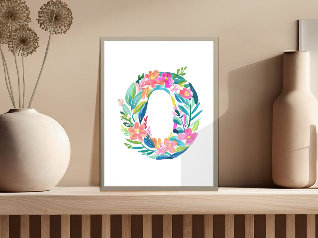 Floral letter O art print in a white frame on a shelf.