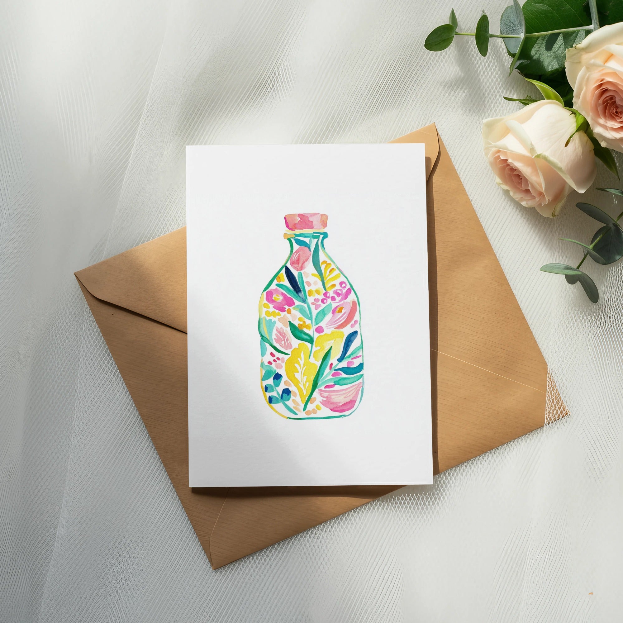 Floral watercolor illustration on card atop brown envelope with roses.