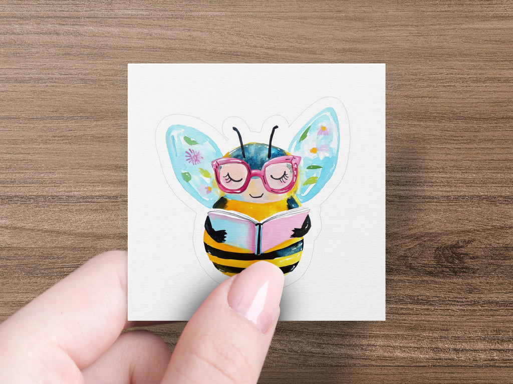 Cartoon bee wearing glasses reads a book.