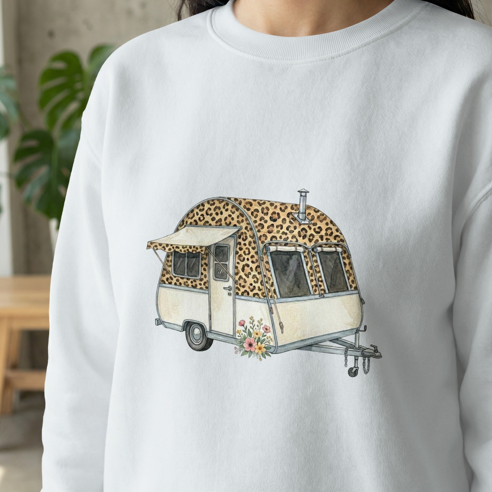 White sweatshirt with a watercolor illustration of a leopard print camper with flowers.
