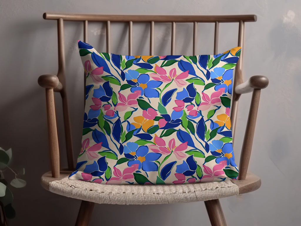 Floral pillow with blue, pink, and yellow flowers on a wooden chair.