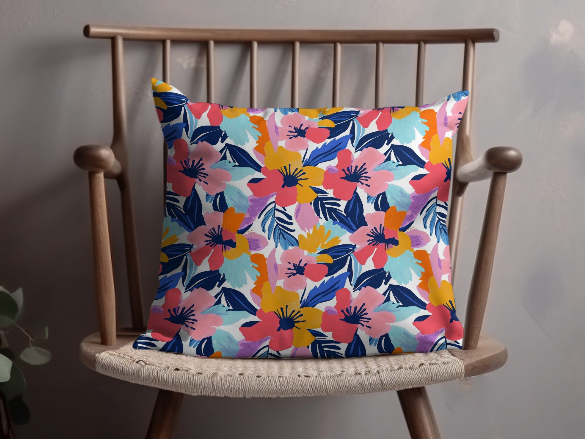 Floral pillow with pink, blue, and yellow flowers on white background.