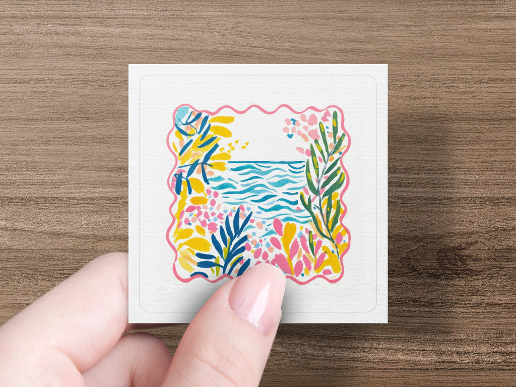Pink, blue, and yellow floral border frames a watercolor ocean and sky.