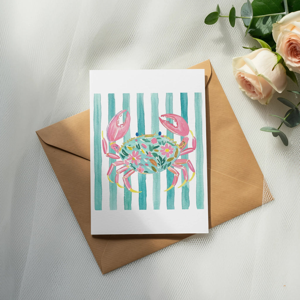Watercolor card with crab illustration on striped background, resting on envelope.