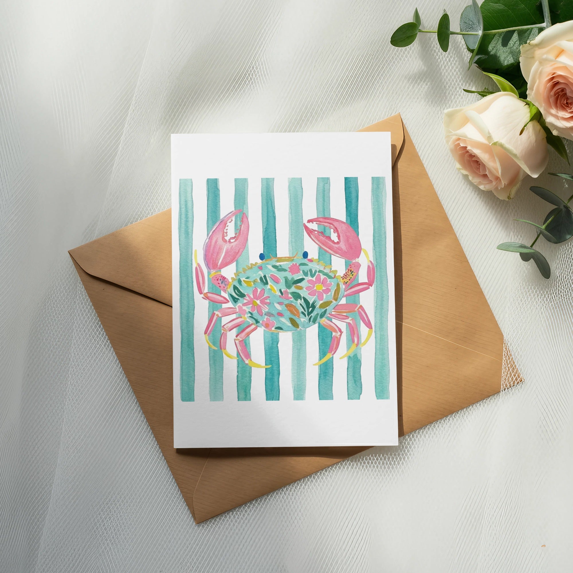 Watercolor card with crab illustration on striped background, resting on envelope.
