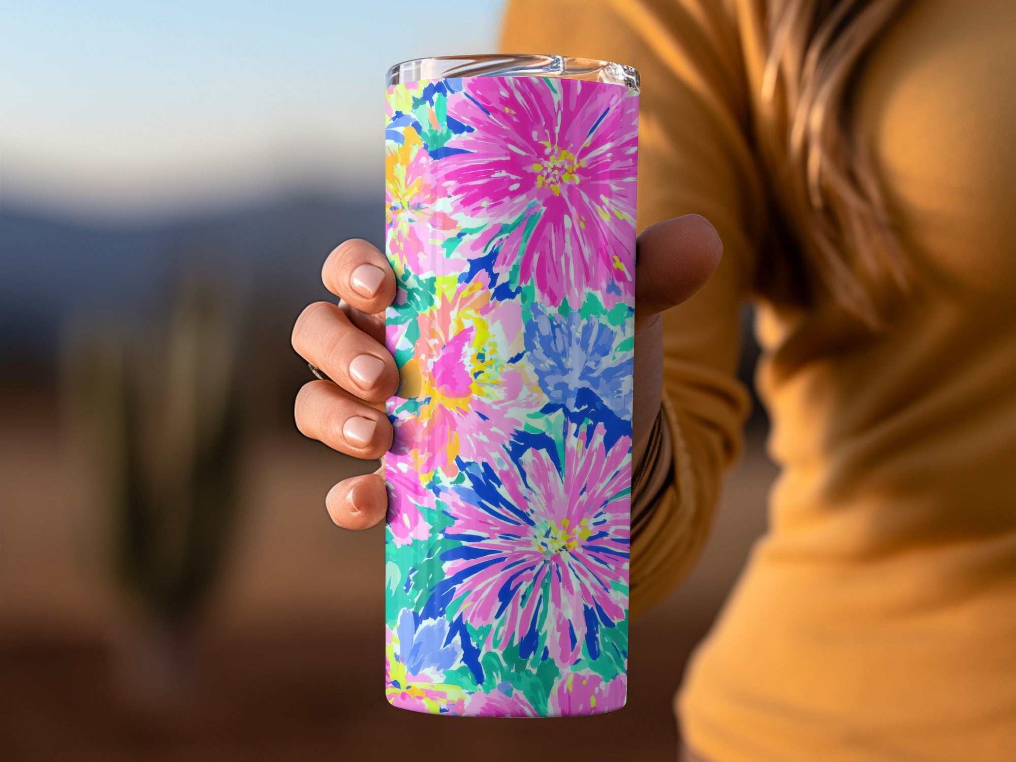 Woman's hand holding a brightly colored floral patterned tumbler.