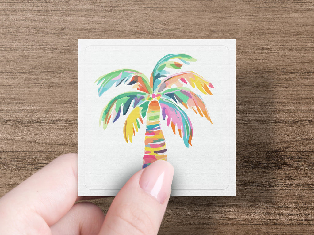 Colorful abstract palm tree illustration on a white card held by a hand.