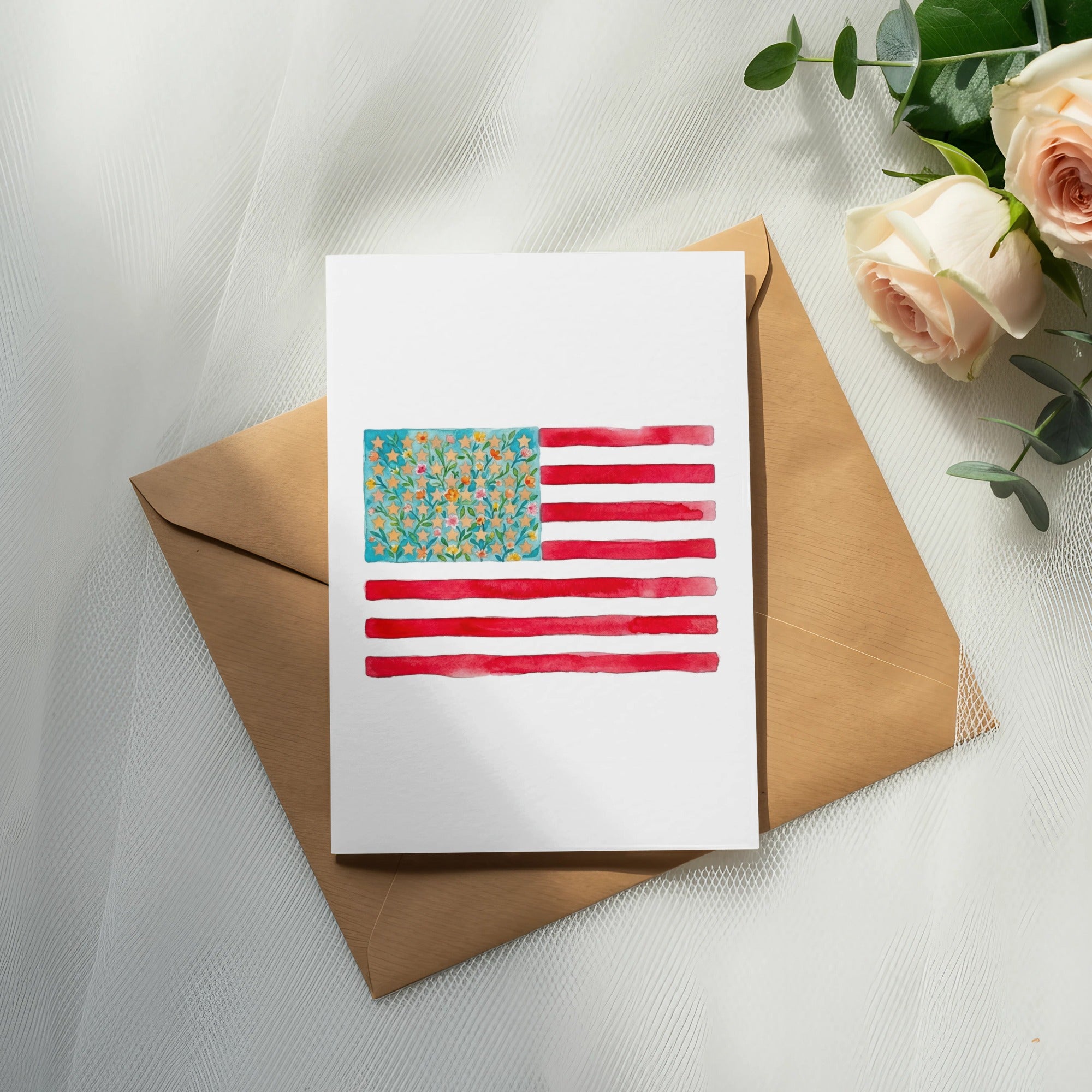 Watercolor American flag card with floral accents on a kraft envelope.
