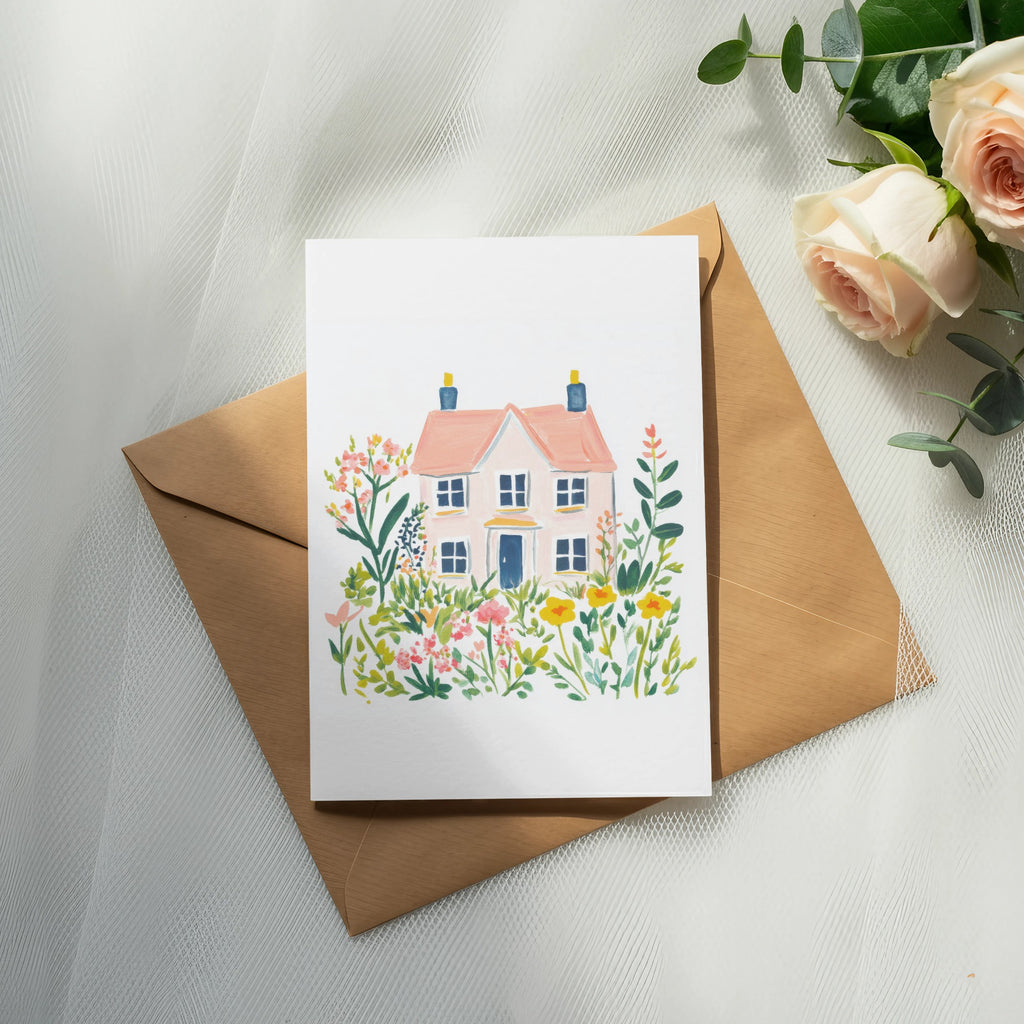 Watercolor illustration of a pink house surrounded by colorful flowers on a kraft envelope.