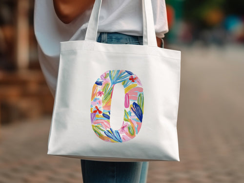 White tote bag with a colorful floral letter O design.