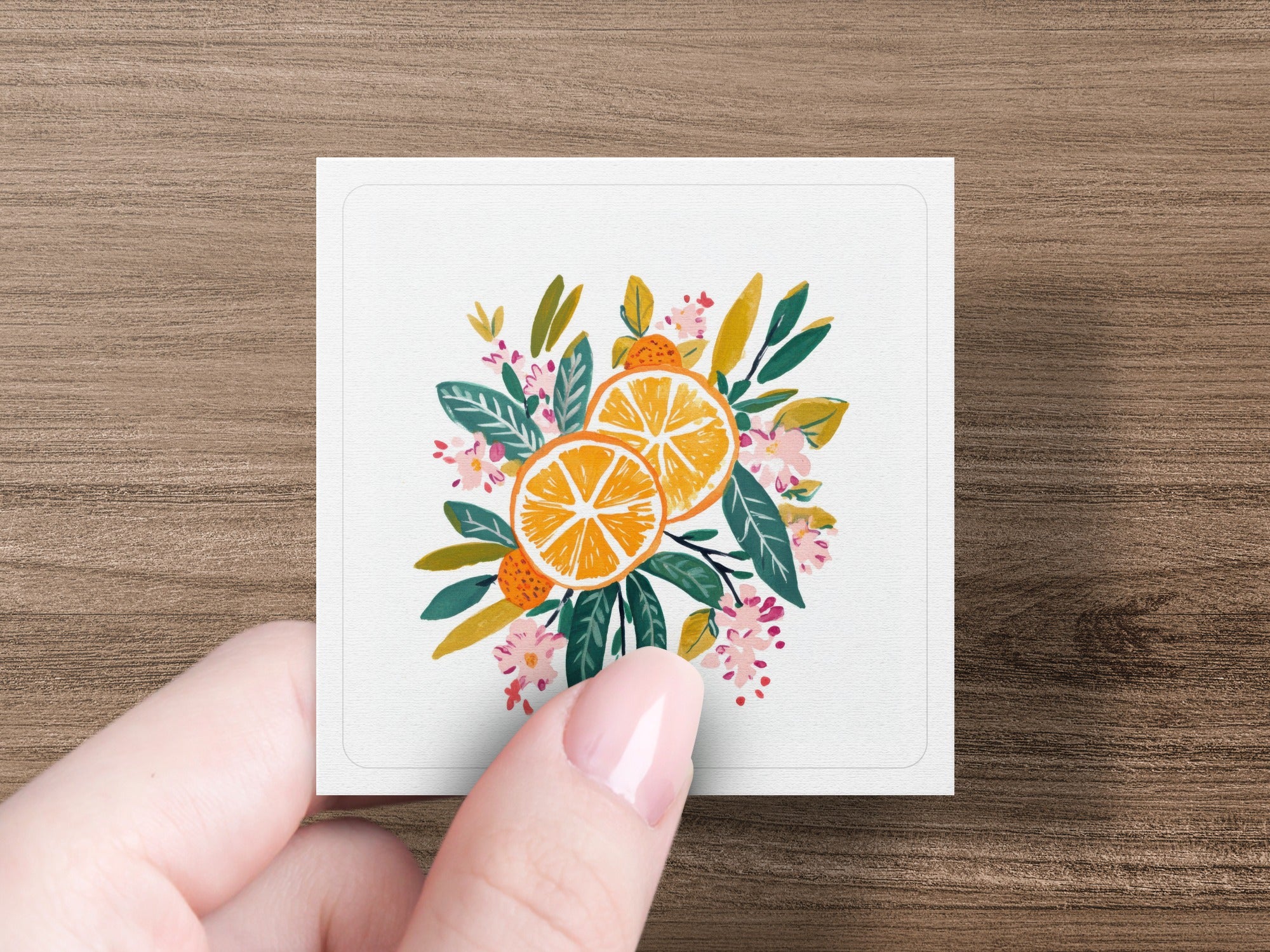 Two orange slices with green leaves and pink flowers.