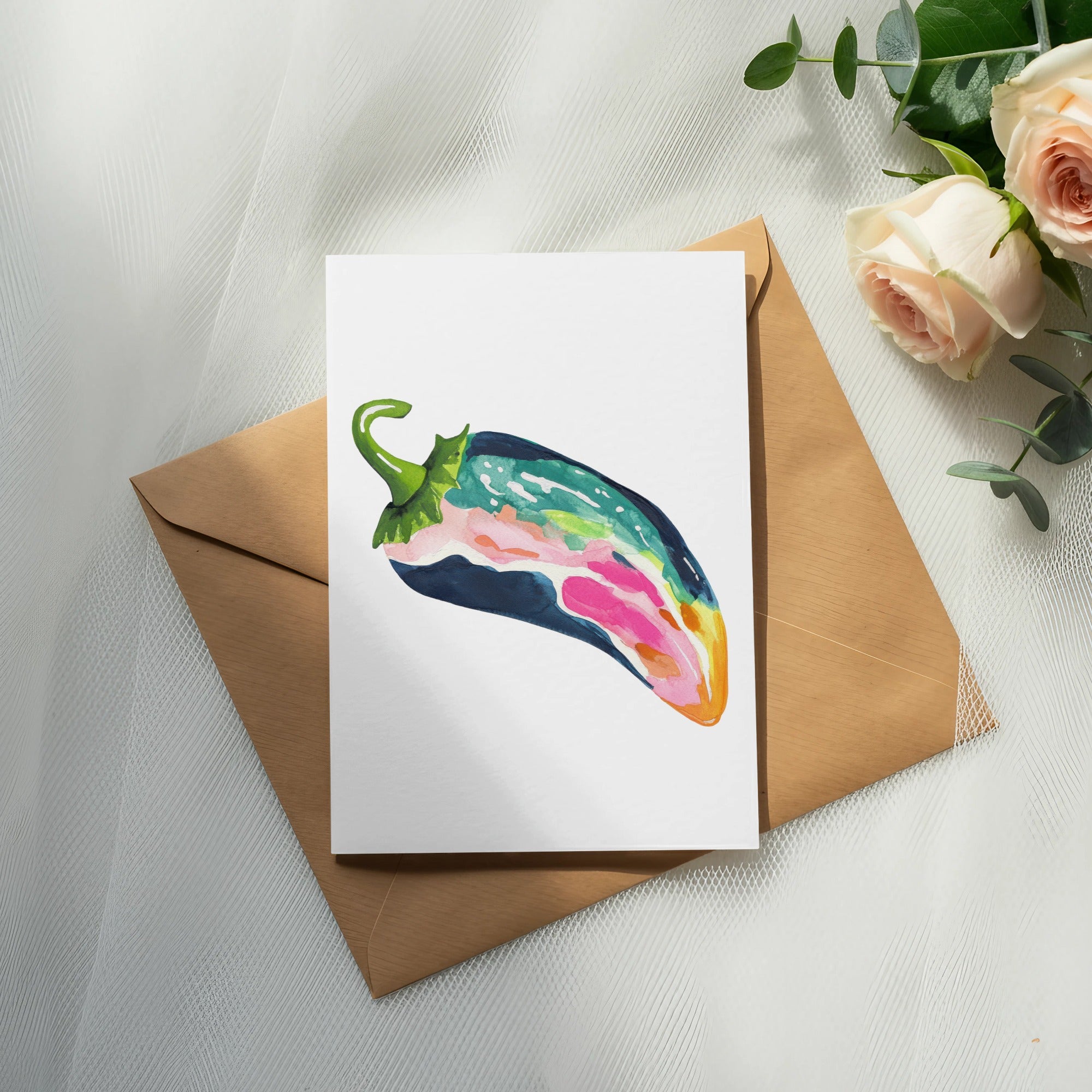 Watercolor illustration of a colorful pepper on a card atop a brown envelope and roses.