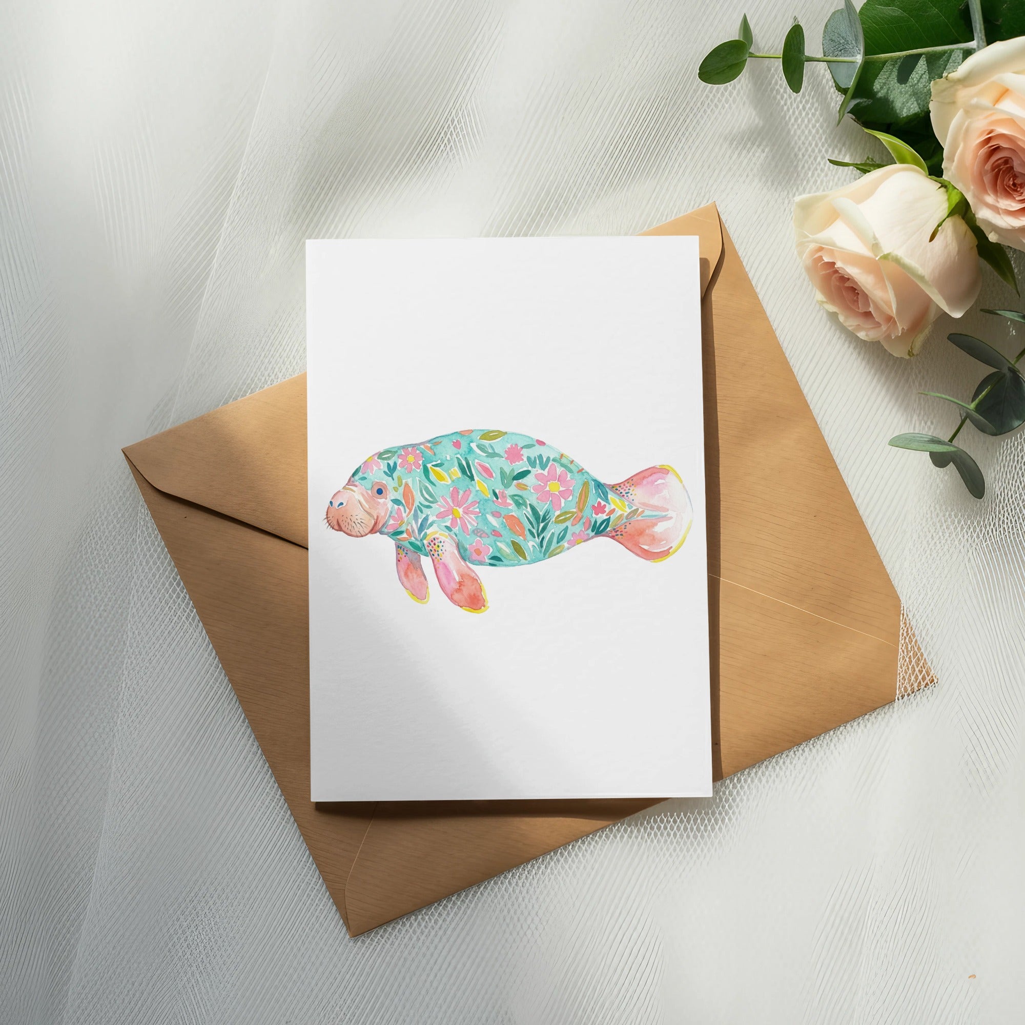 Watercolor manatee with floral pattern on card resting on brown envelope.