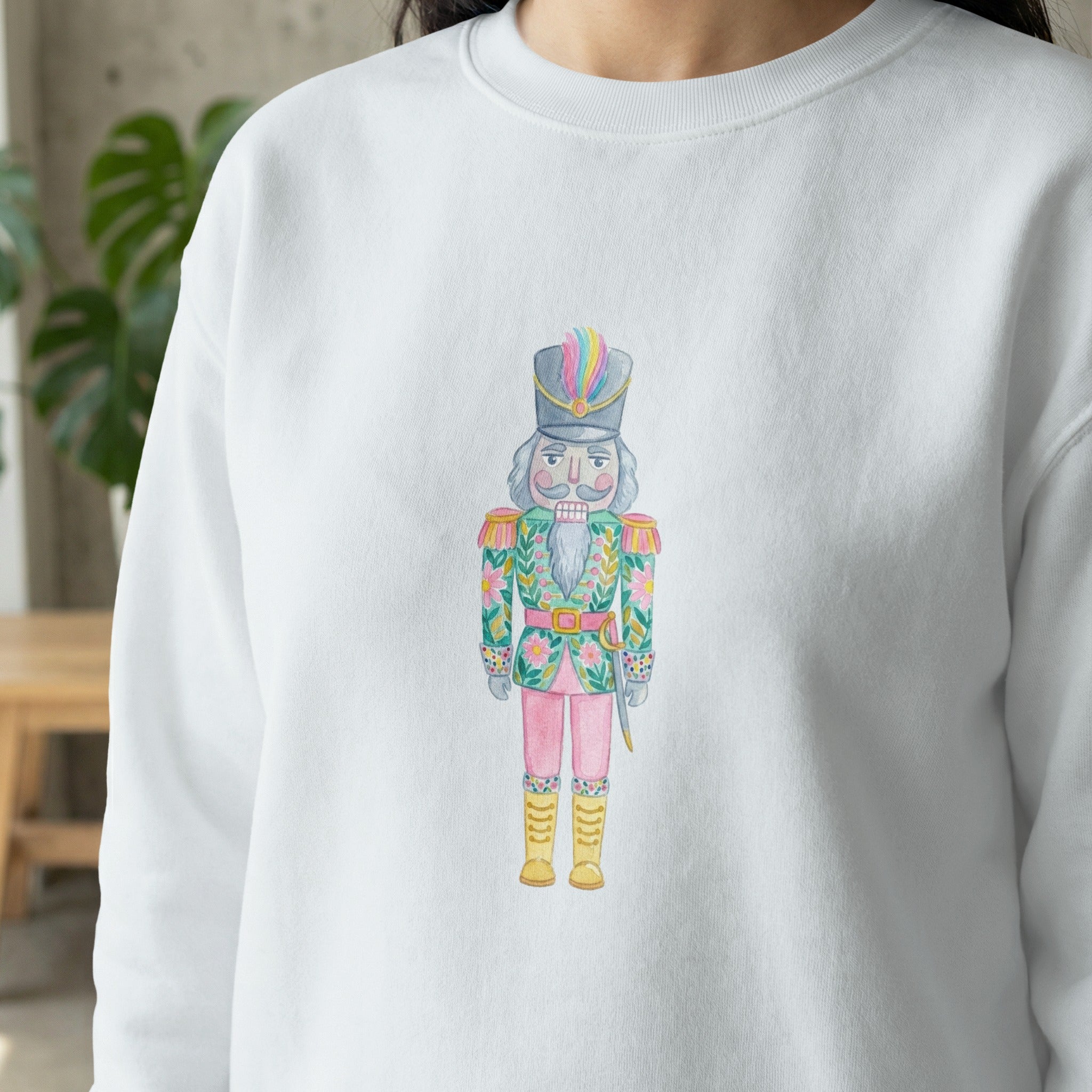 White sweatshirt with a watercolor nutcracker wearing a colorful uniform.