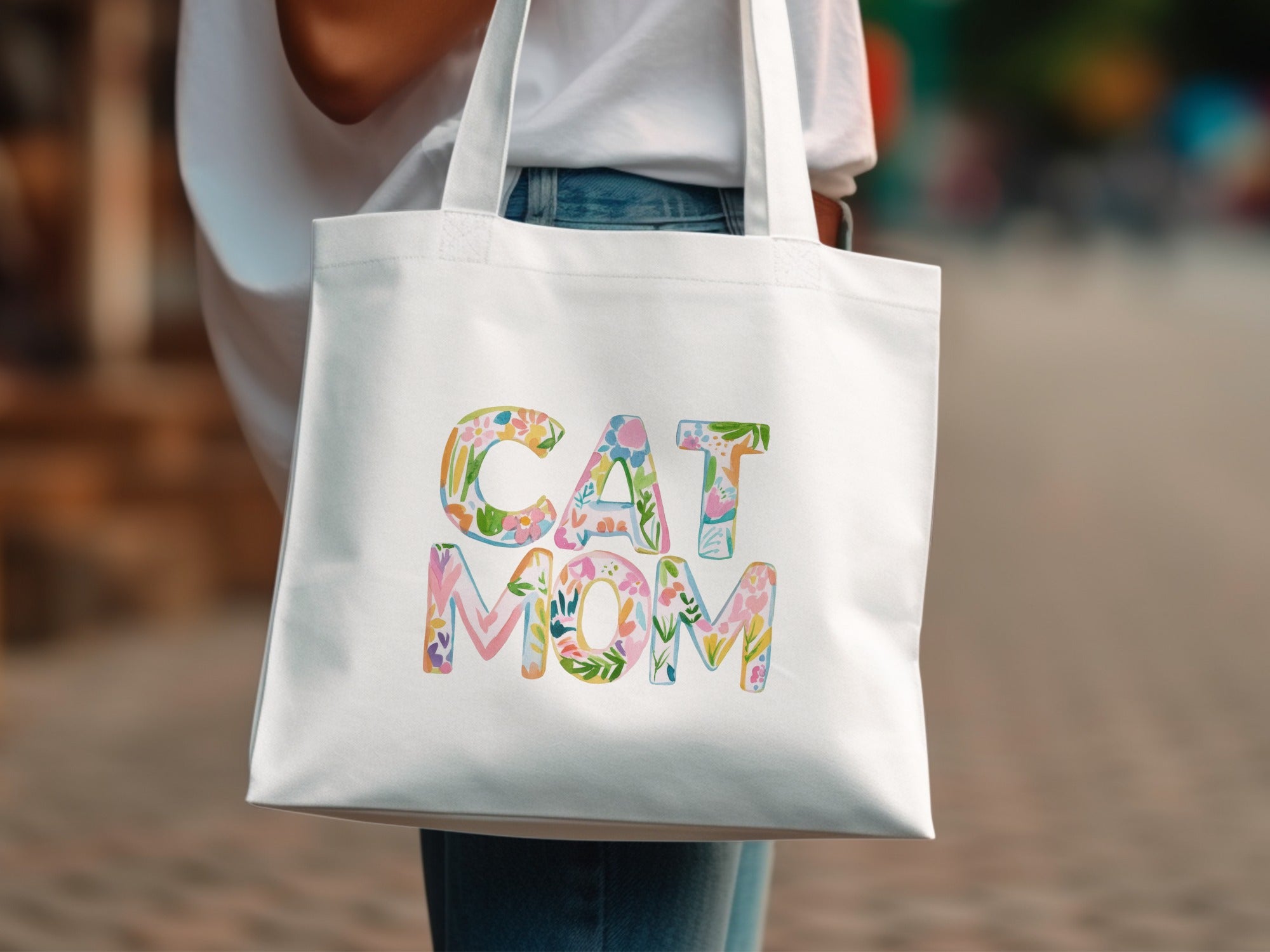 White tote bag with colorful floral "CAT MOM" text.