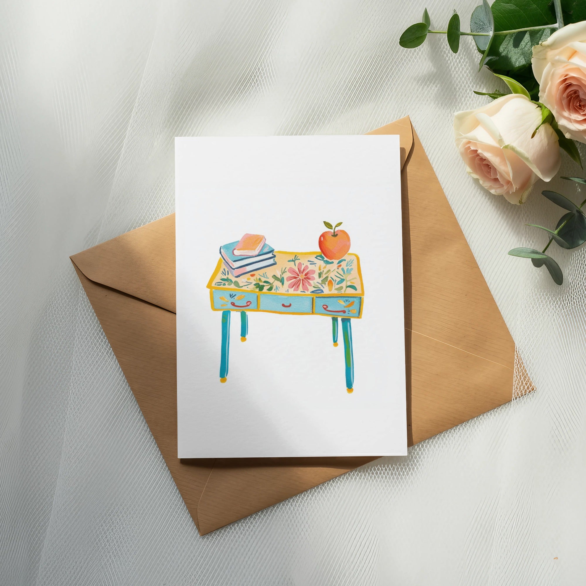Card with colorful desk illustration, books, and apple on envelope.