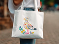 White tote bag with colorful abstract bird and floral design.