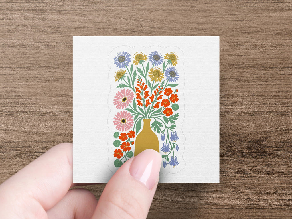 Folk art vase with orange, blue, and yellow flowers on white background.