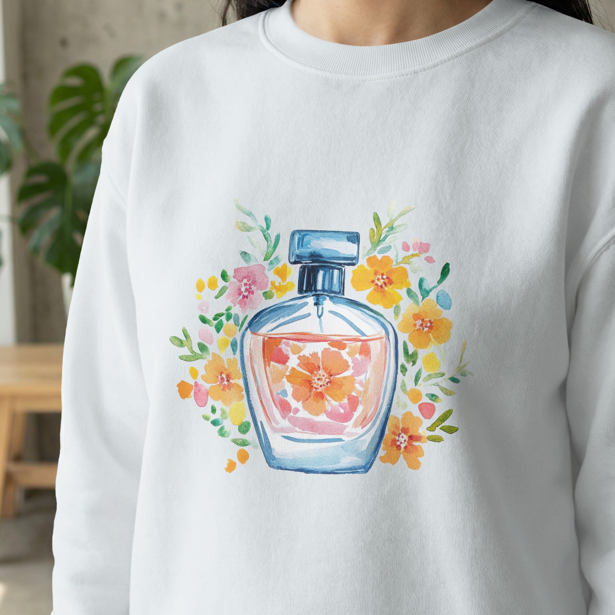 Watercolor perfume bottle with floral accents on white sweatshirt.