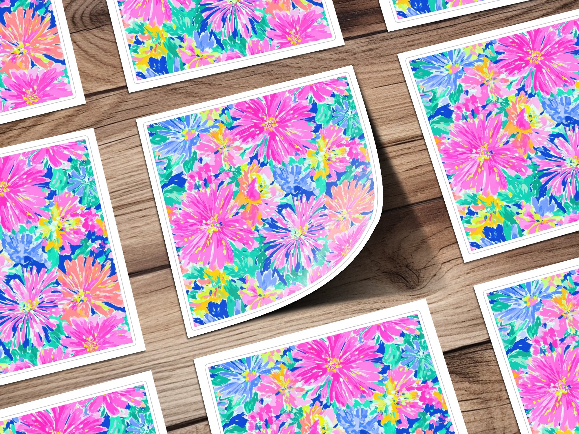 Several square cards with a bright floral pattern arranged on a wooden surface.