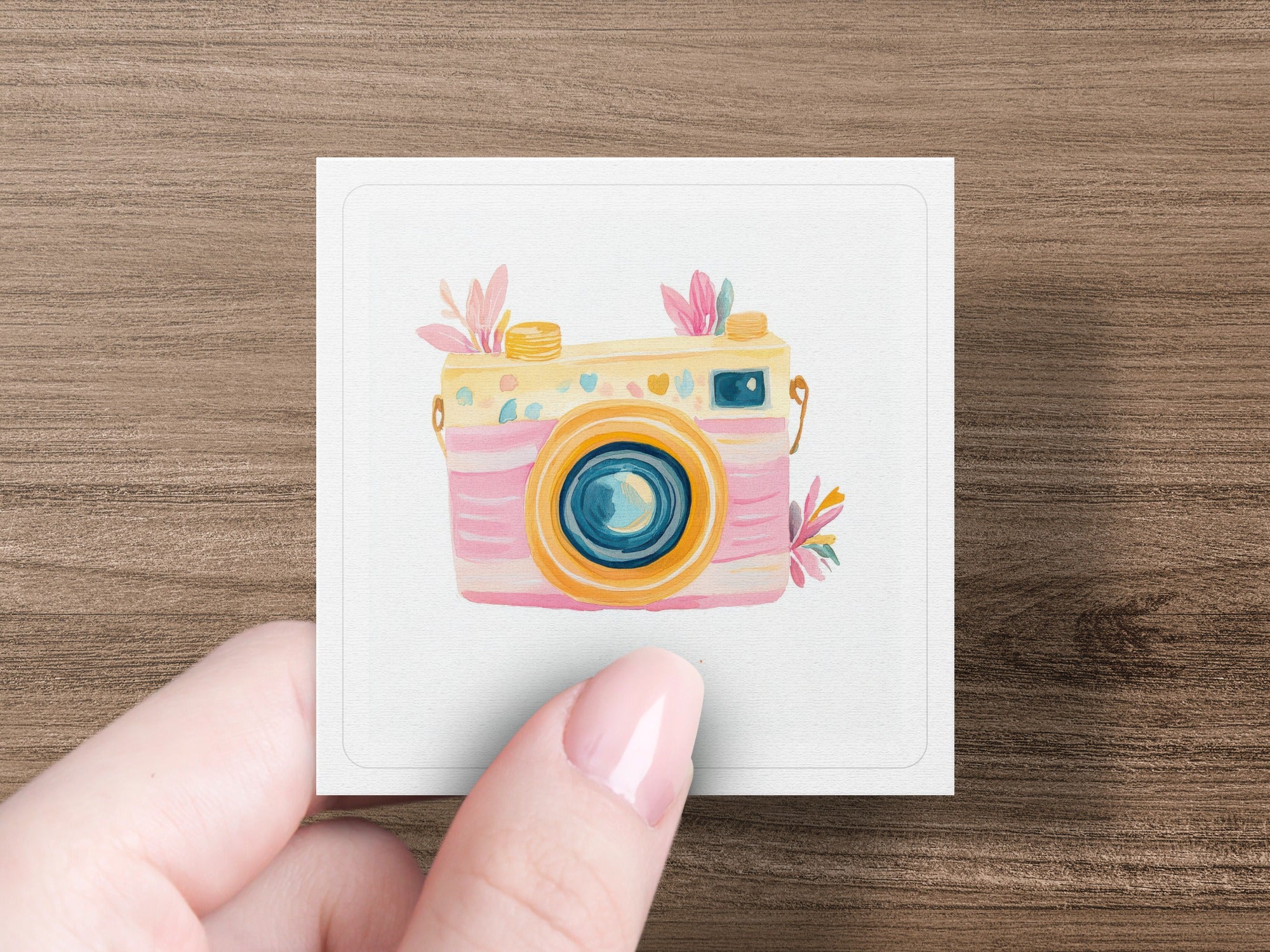 Pink and yellow toy camera with flowers, held by a hand.