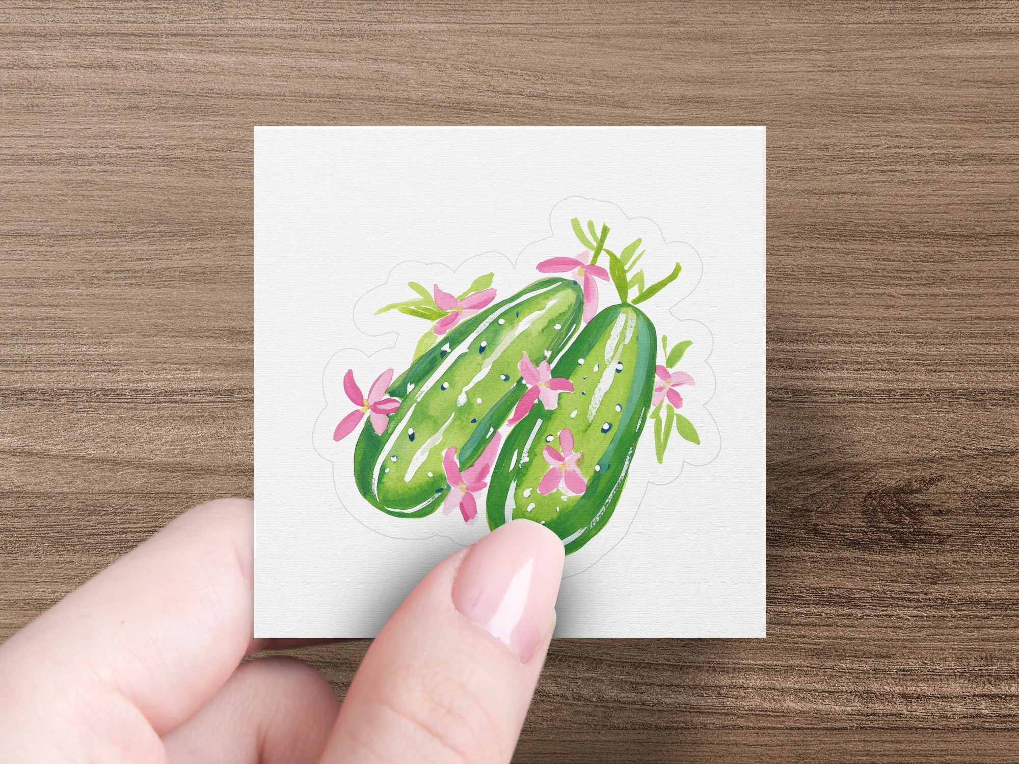 Two green cucumbers with pink flowers and leaves.