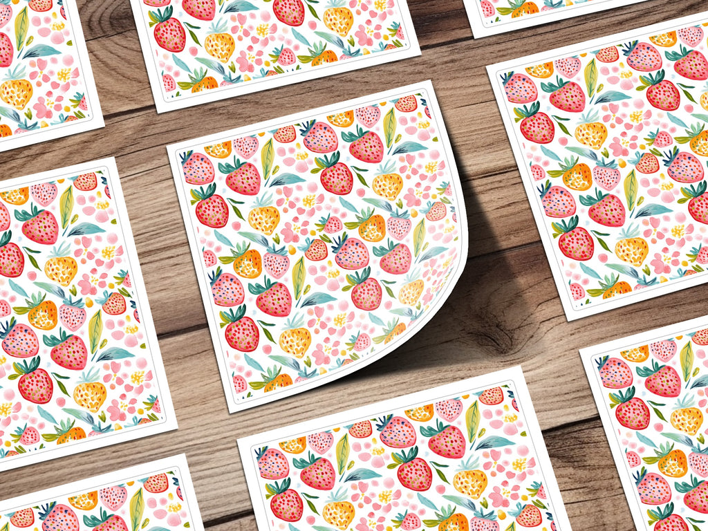 Watercolor strawberries and pink flowers pattern on cards, laid out on wood.