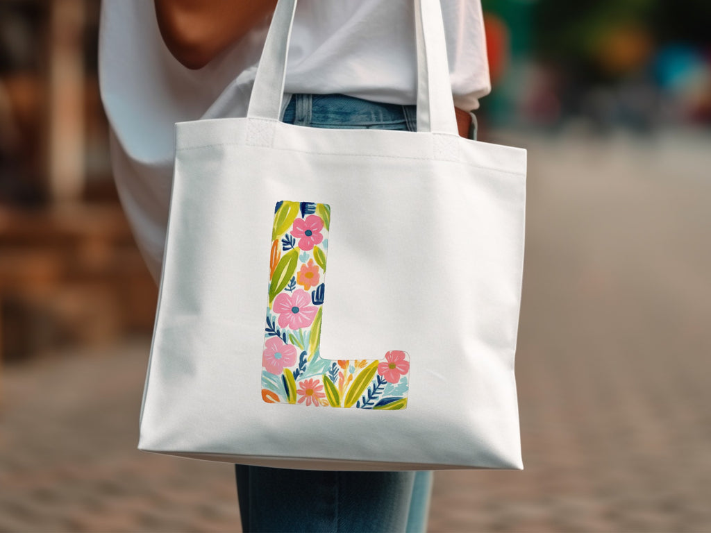 White tote bag with large colorful floral letter L design.