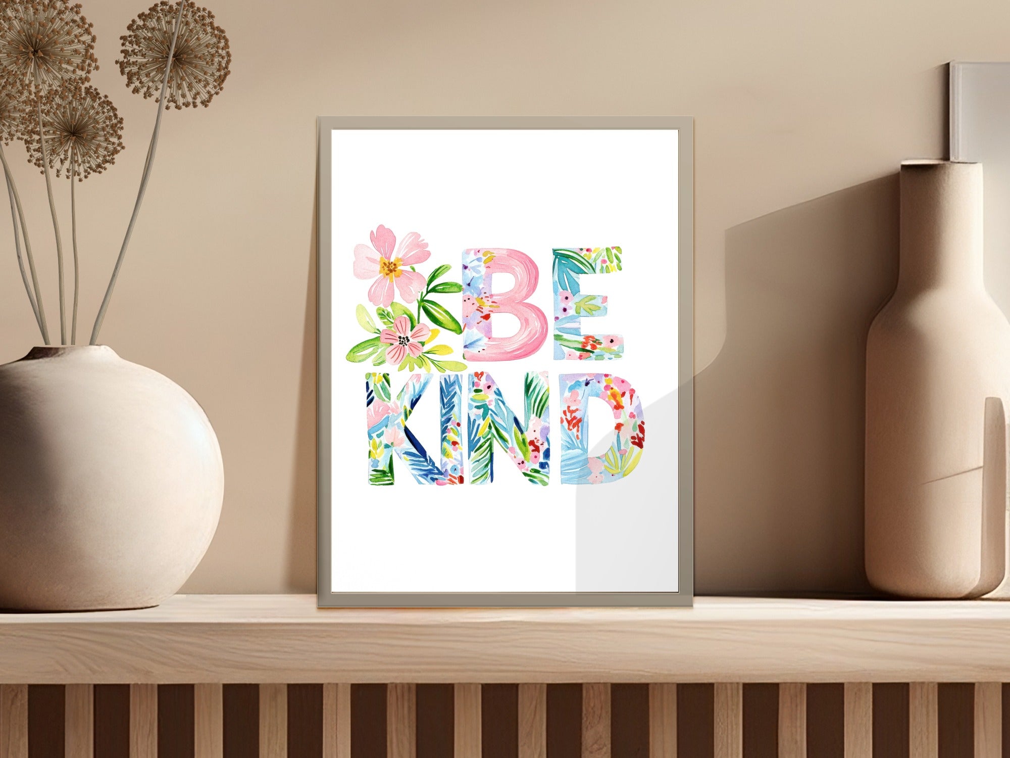 "BE KIND" text art with floral watercolor accents on a white background.