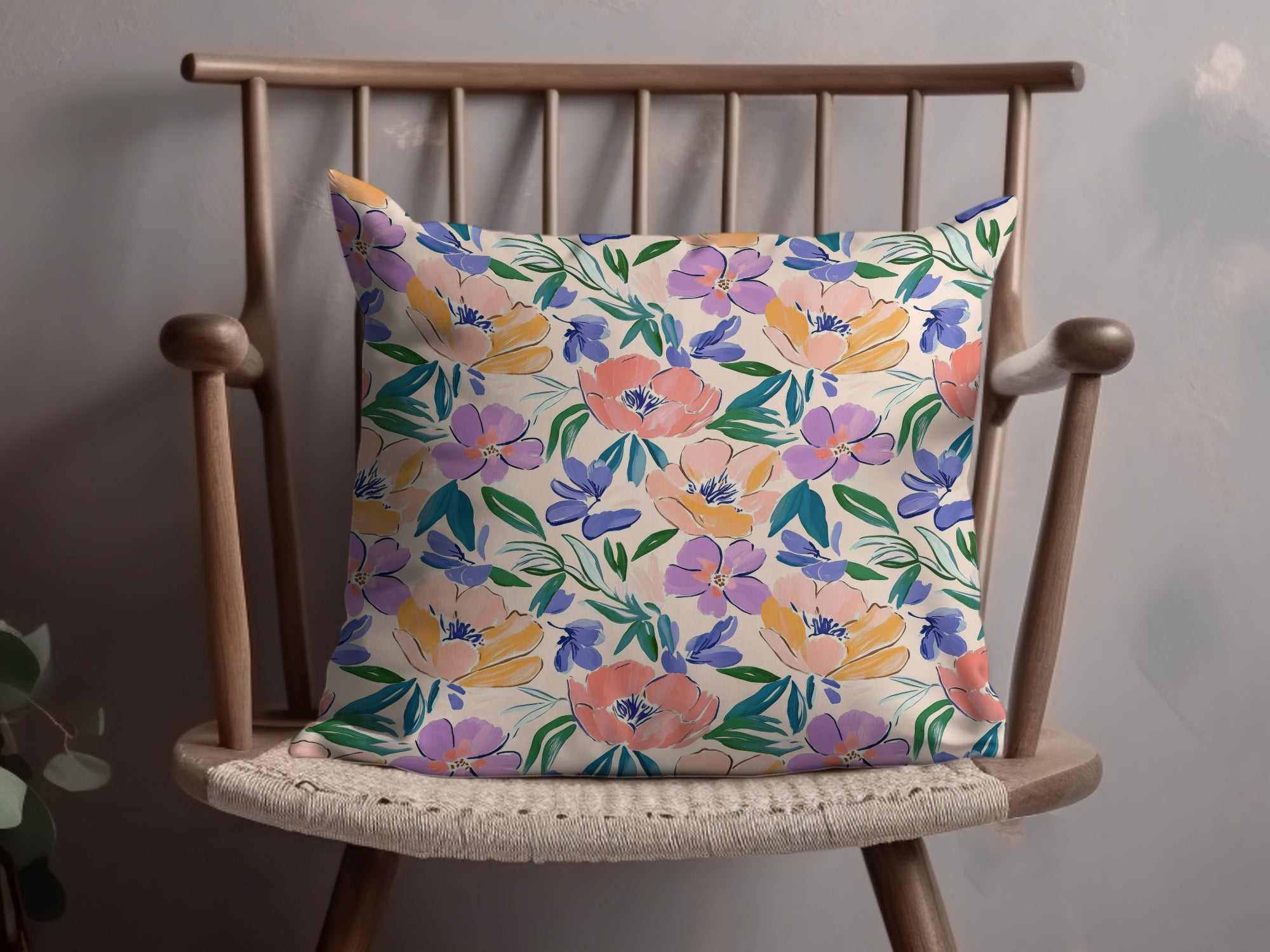 Floral patterned throw pillow on a wooden chair.