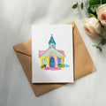 Watercolor illustration of a colorful church on a kraft paper envelope.