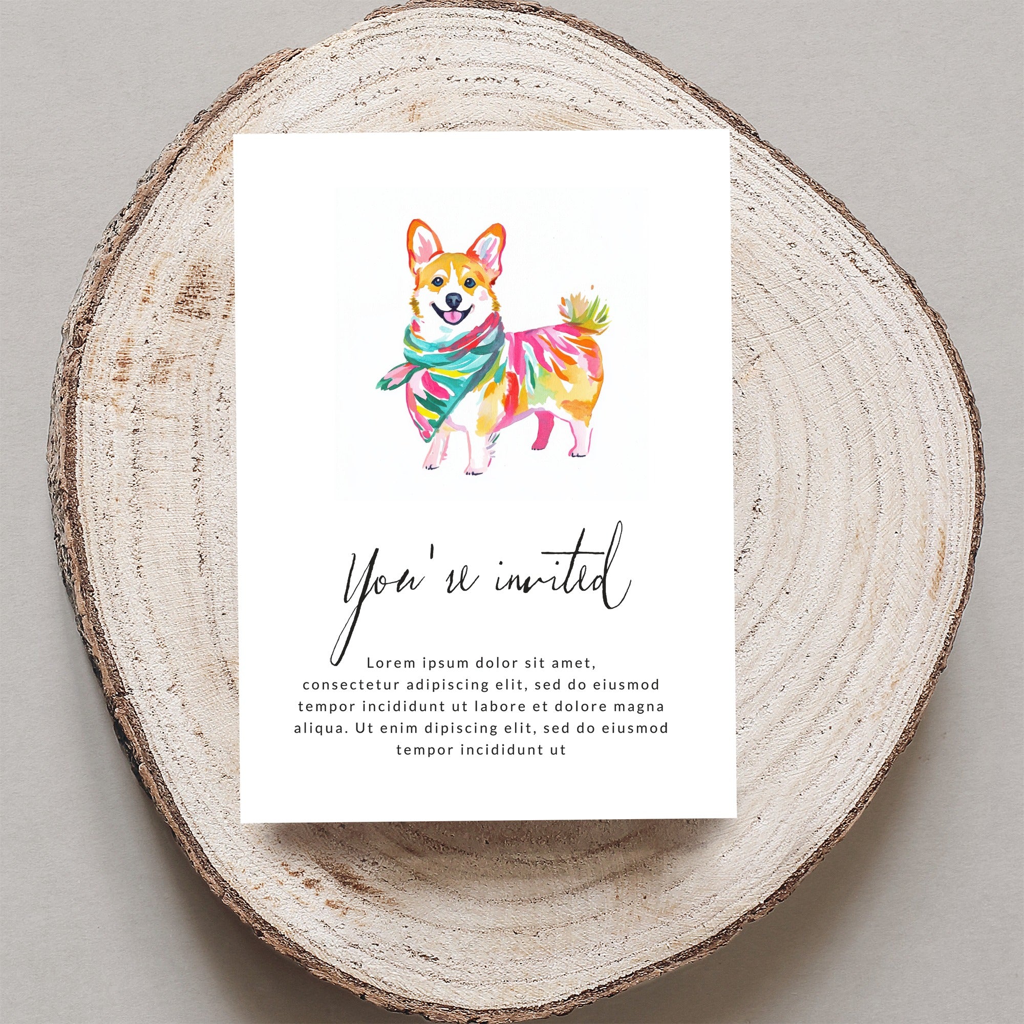 Card with corgi illustration and "You're invited" text, on wood slice.