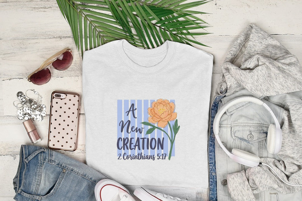 White t-shirt with "A New Creation" and floral graphic, 2 Corinthians 5:17.