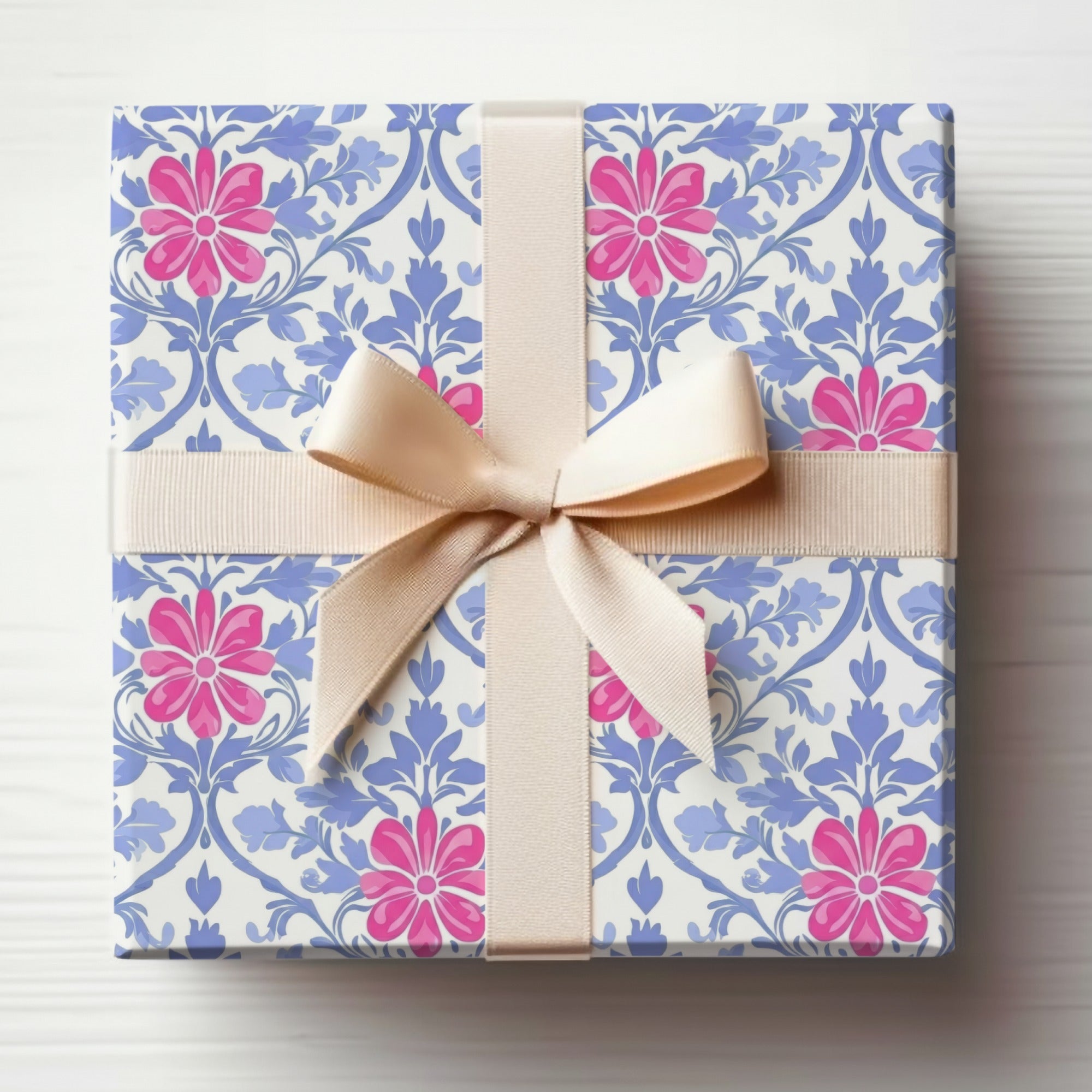 Gift box with pink flowers and blue scrolling pattern, tied with a beige ribbon.