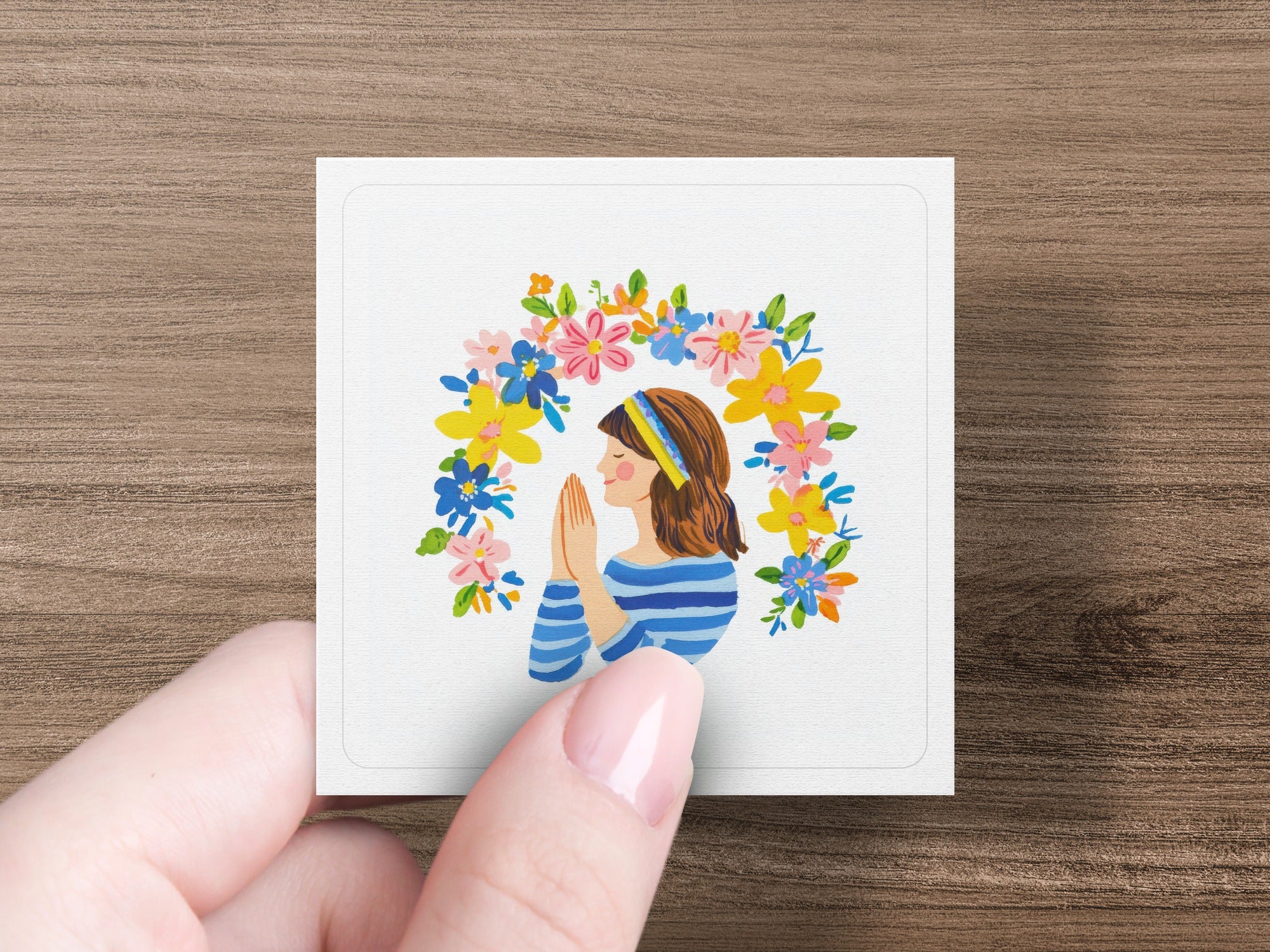 Woman with hands clasped in prayer, surrounded by a floral wreath.