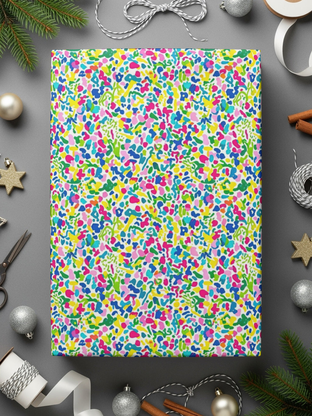 Wrapping paper with a colorful abstract splatter pattern, surrounded by ribbons and Christmas decorations.