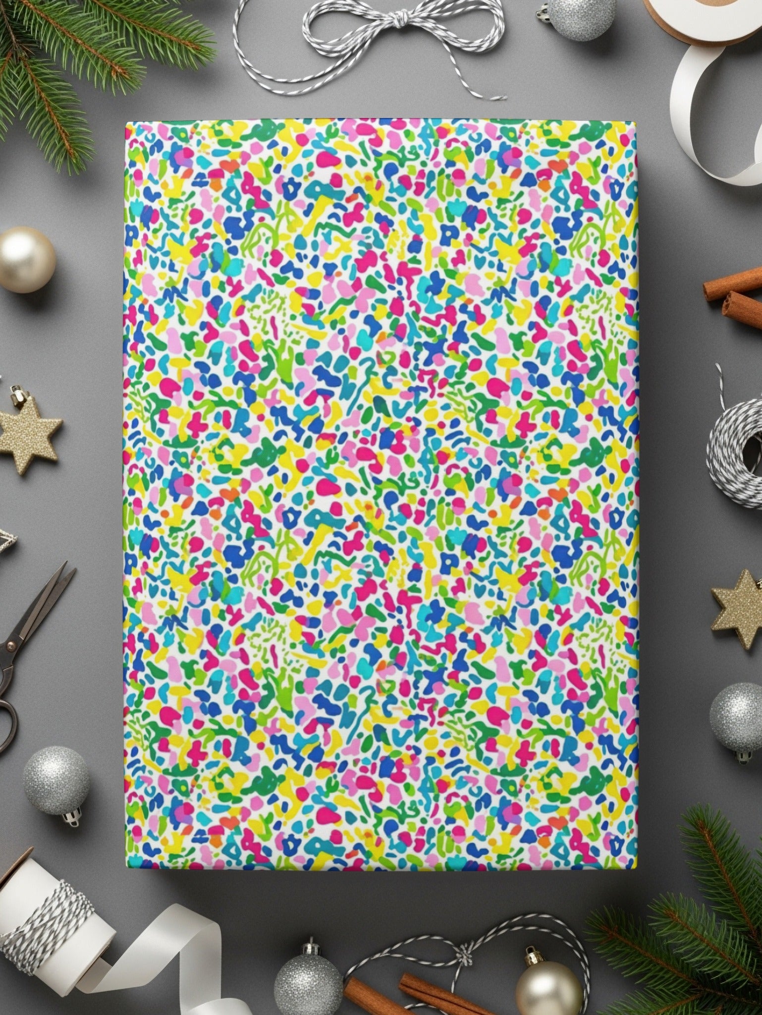 Wrapping paper with a colorful abstract splatter pattern, surrounded by ribbons and Christmas decorations.