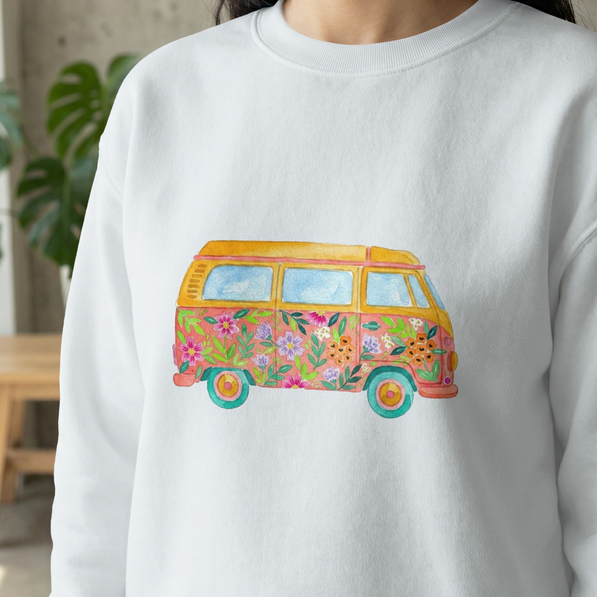White sweatshirt featuring a colorful watercolor illustration of a vintage van adorned with flowers.