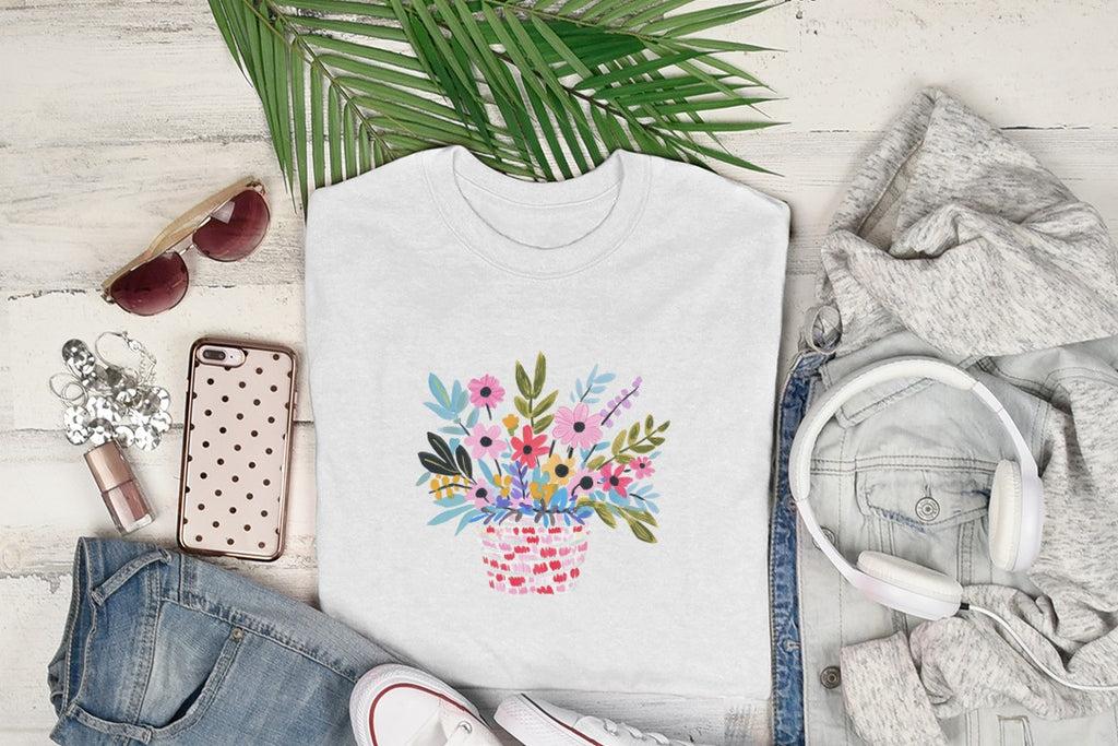 White t-shirt with colorful floral basket graphic, styled with jeans and headphones.