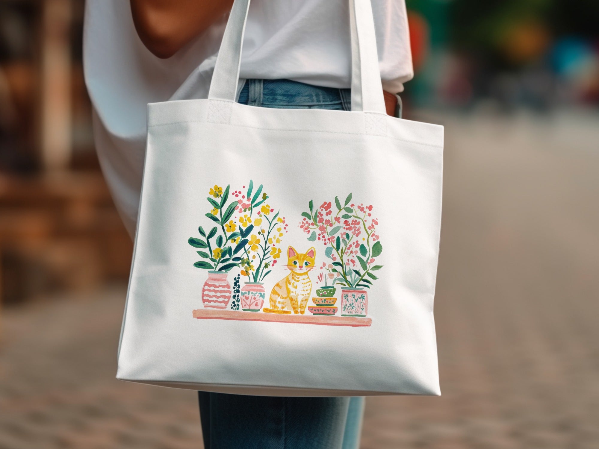 White tote bag with a watercolor painting of a cat and potted plants.