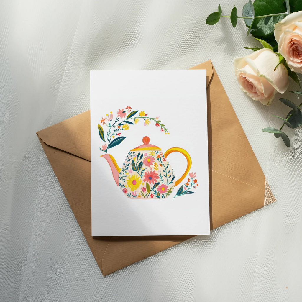Floral teapot illustration on a card atop a brown envelope.