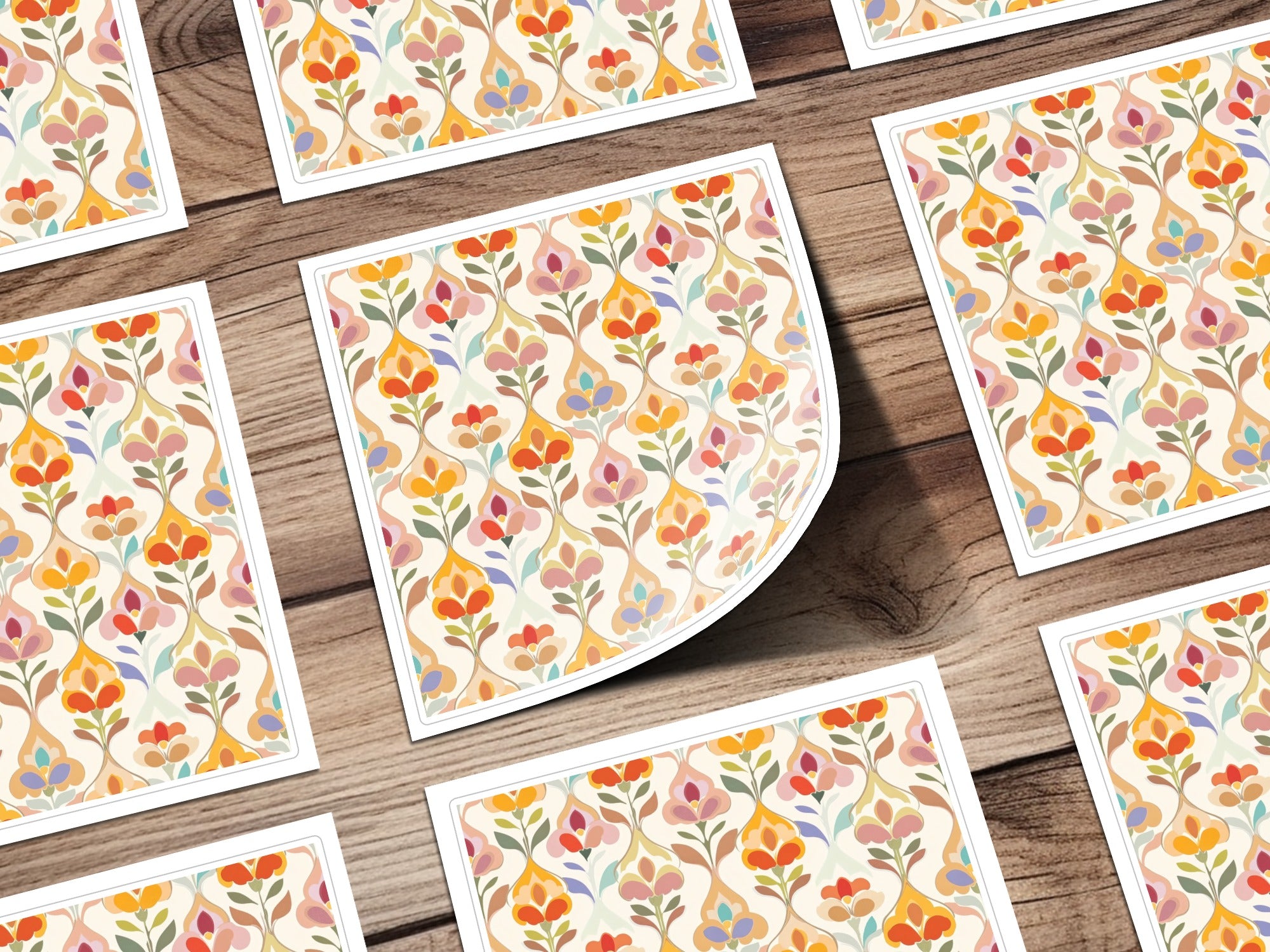 Scattered floral pattern cards with orange, blue, and yellow accents on wood grain background.