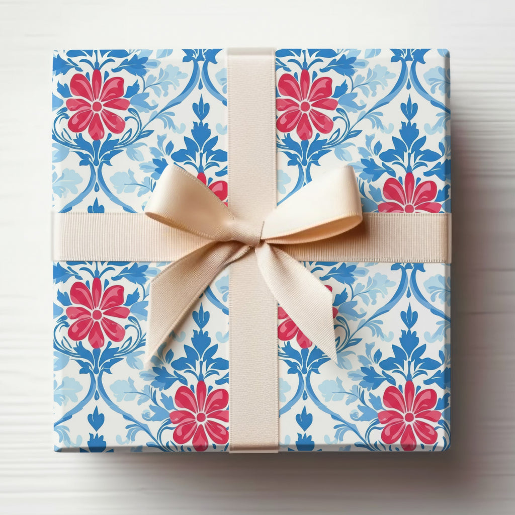 Gift box with red flowers and blue floral pattern tied with a cream ribbon.